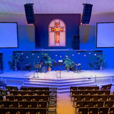 A church with a cross on the wall and a large stage.