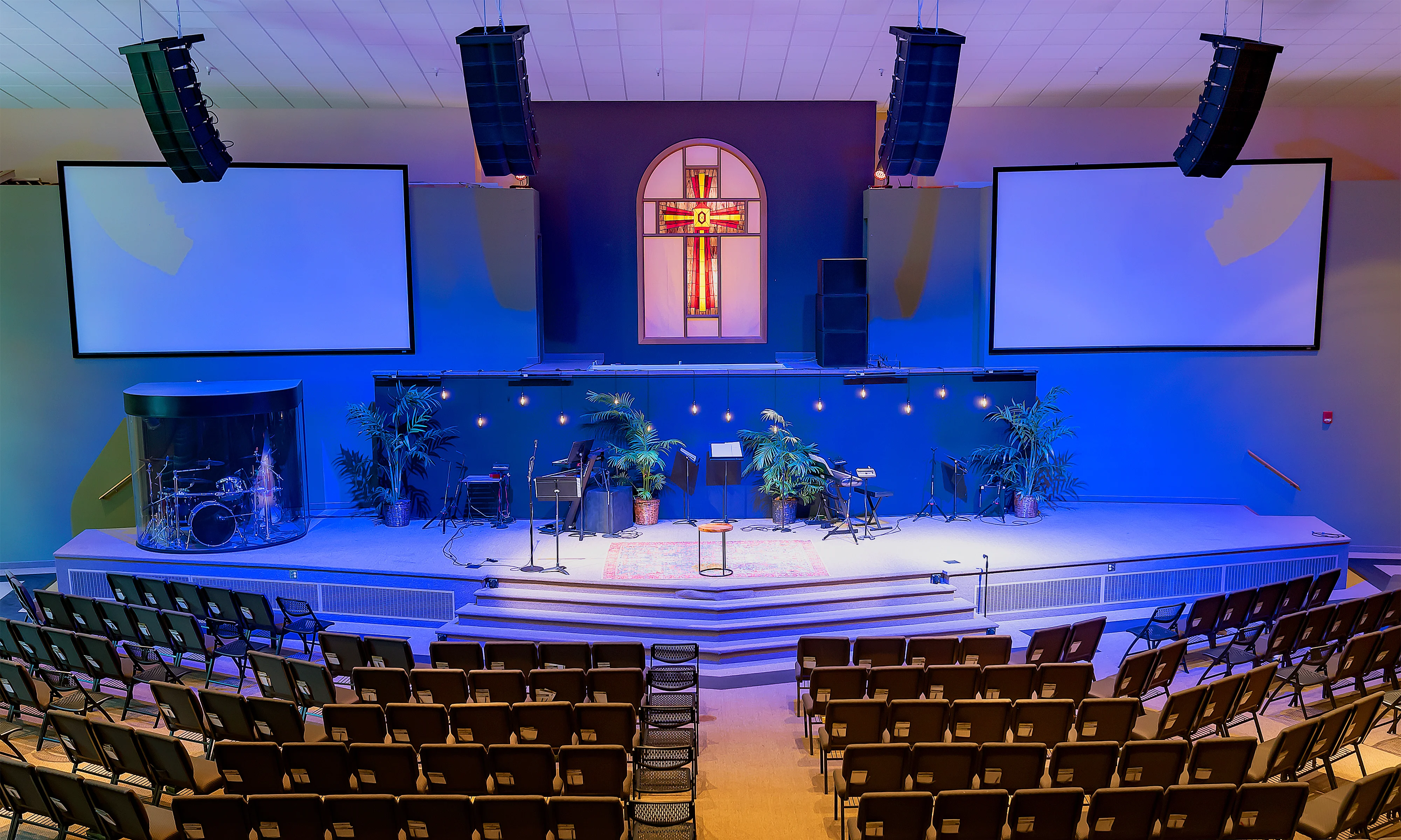 A church with a cross on the wall and a large stage.